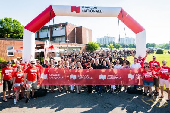 Photo of a group of employees dressed in red holding a banner with the National Bank logo at the end of a race