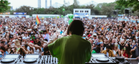 Photo of a DJ performing at an outdoor concert in front of a full crowd 