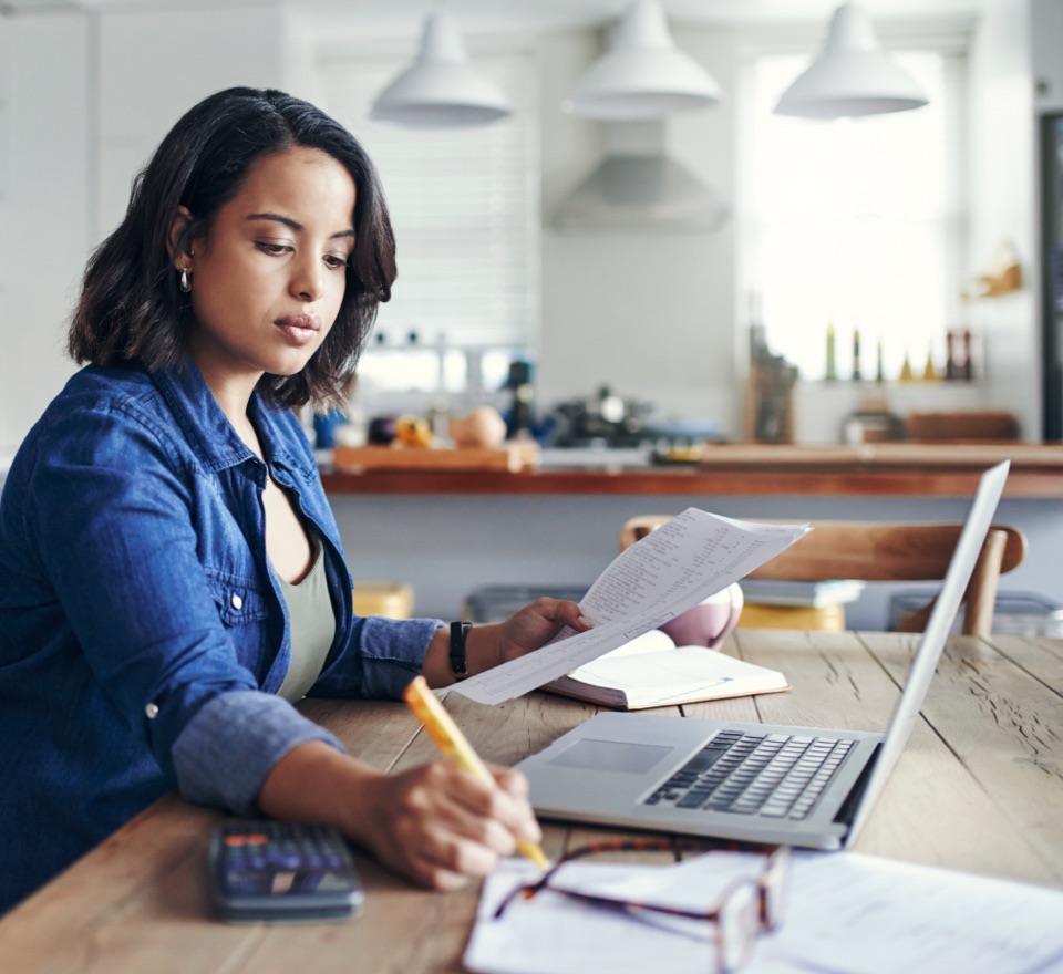 Photo of a woman sitting at a table working on their laptop