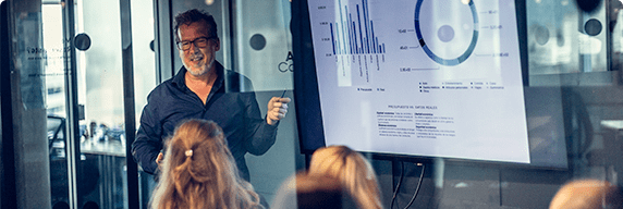Photo of a man leading a meeting and presenting results on graphs 