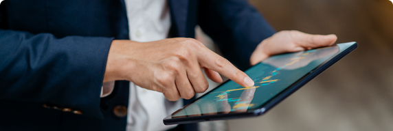 Picture of a person holding a tablet while pointing at a graph on the tablet 