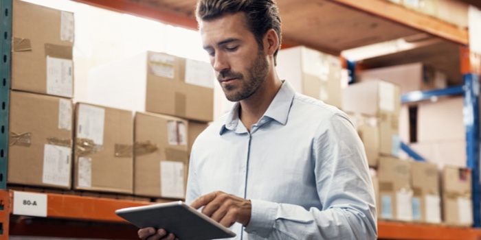 Man in a warehouse looking at his tablet