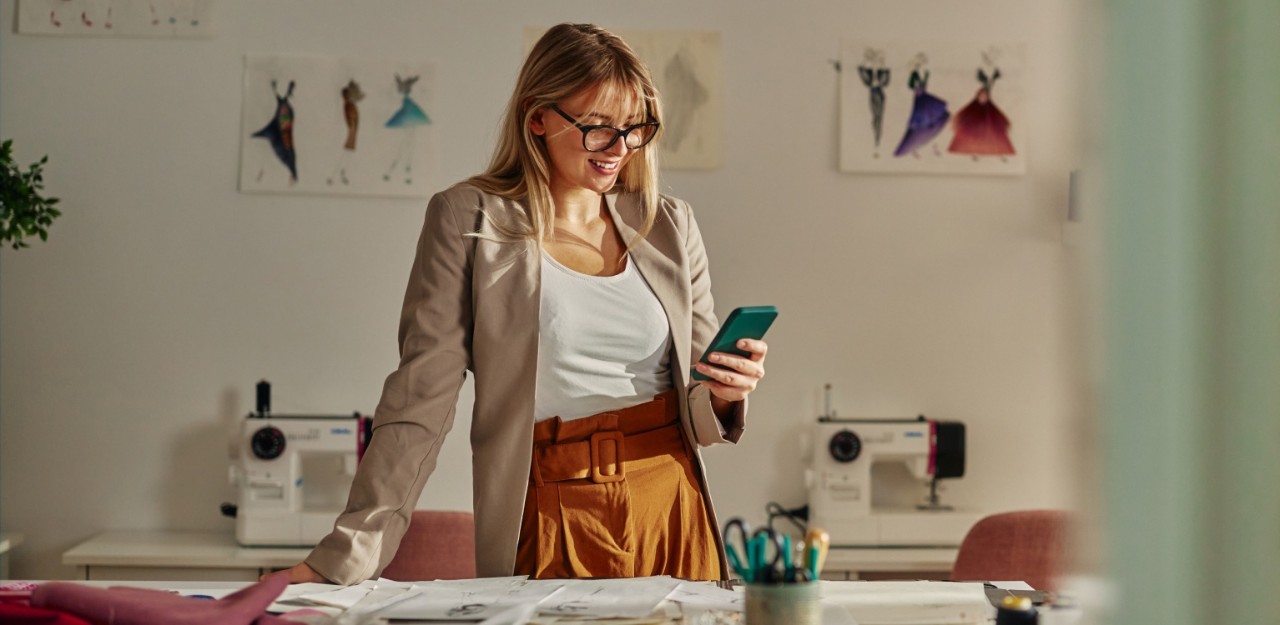 Photo of a person smiling while looking at their phone in an office
