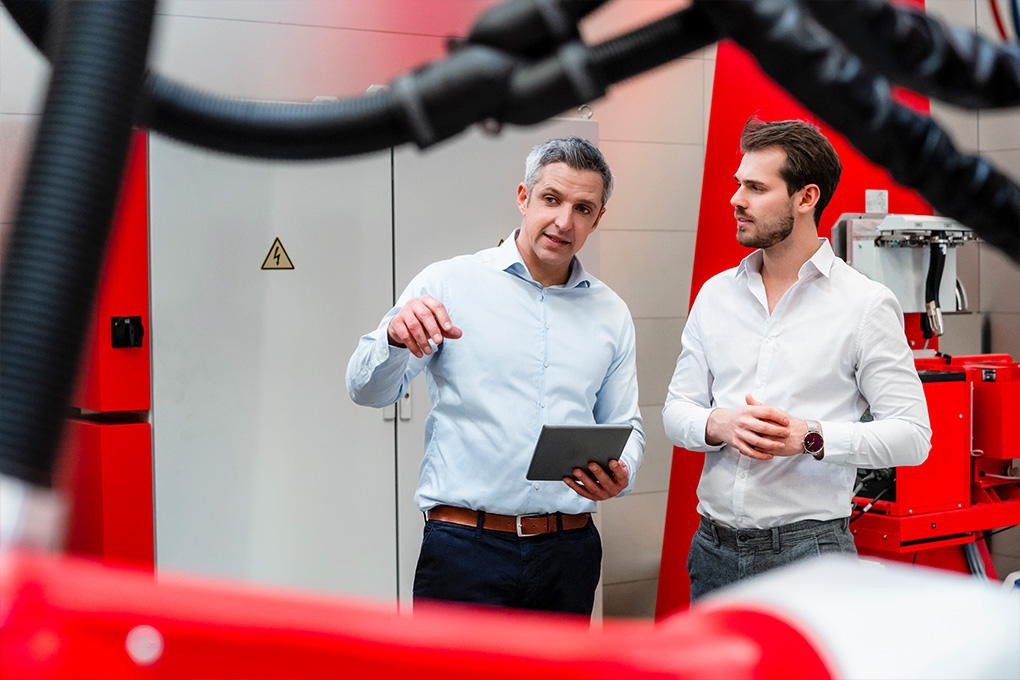 Two men standing in front of a machine, watching intently.