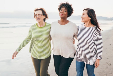 Three retired women walking on the beach