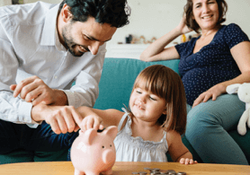 A couple with their daughter playing with a piggybank 