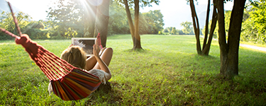 Woman in a hammock surfing the Internet on a tablet