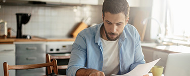 Man looking at papers in his kitchen