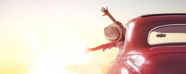 Young woman in a car reaches out to the sun