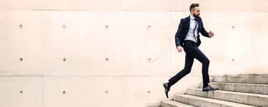 Young man in a suit running up a flight of stairs