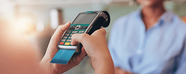 Person holding a payment terminal and entering his pin