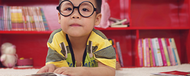 Child with glasses reading a book