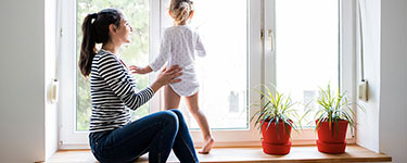Woman helping her young daughter to stand up