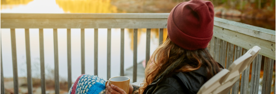 Young woman sitting on a balcony in front of a lake