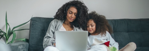 Woman and little girl on sofa looking at laptop