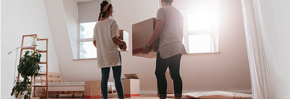 Young couple carrying boxes in an empty house