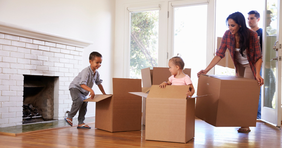 Children playing in boxes while parents move into new home