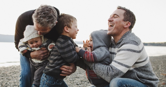 Two men playing with children by a lake