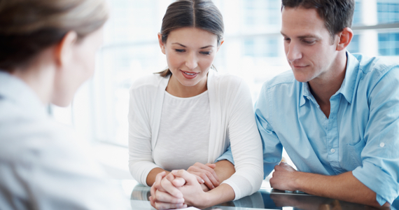 Young couple holding hands is sitting at a table with a woman