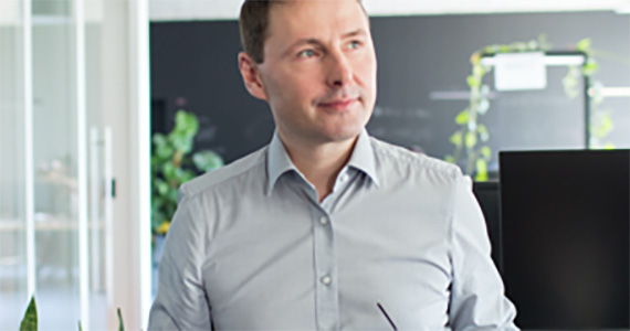 Photo of a pensive man standing in a brightly lit office