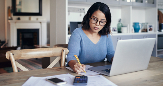 Woman sitting in her dining room works on her computer