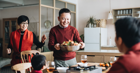 Happy couple bringing a dish to the table for their two children. 