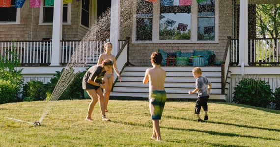 Children play in a sprinkler on a lawn