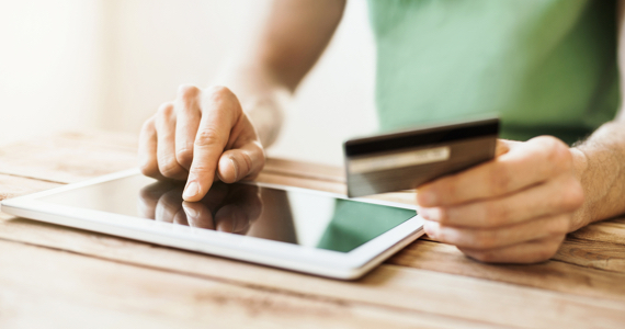Man's hands handling a credit card and using a tablet
