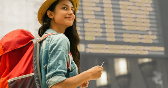 A young woman with a backpack smiles in a train station