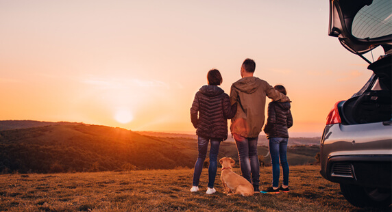 A family on a hill looking off into the sunset
