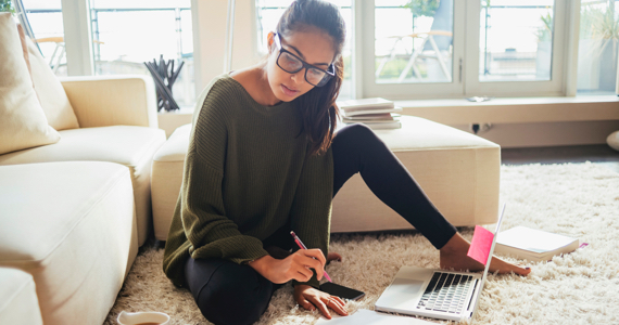Young woman studying on the carpet of her living room