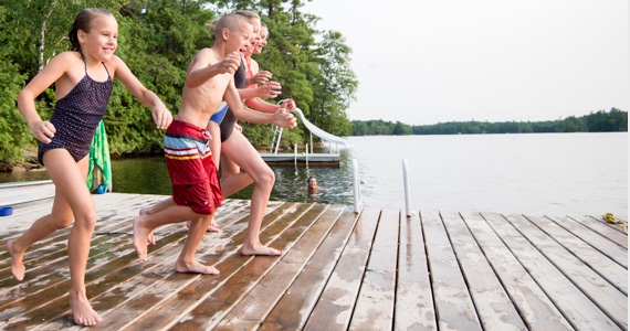 Children run to dive into a lake