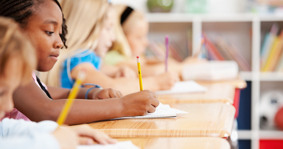 Children in a classroom write in a notebook