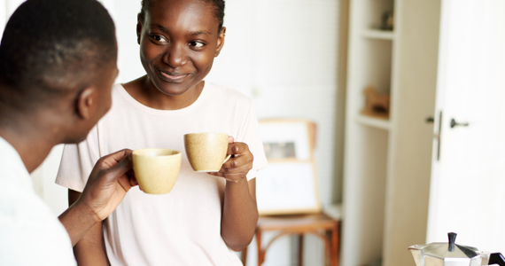 Man and woman look at each other while holding a cup of coffee