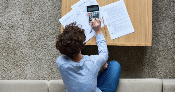 Woman seen from above does calculations with a calculator