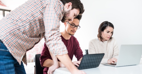 Three people working together while looking at their computers