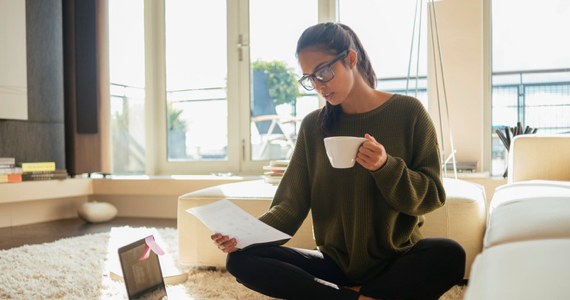 Woman with glasses drinking coffee and looking at documents