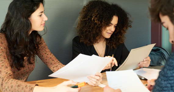 Two women and man looking at documents