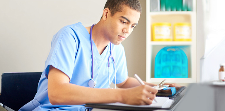 A medical student writing with a stethoscope around their neck.