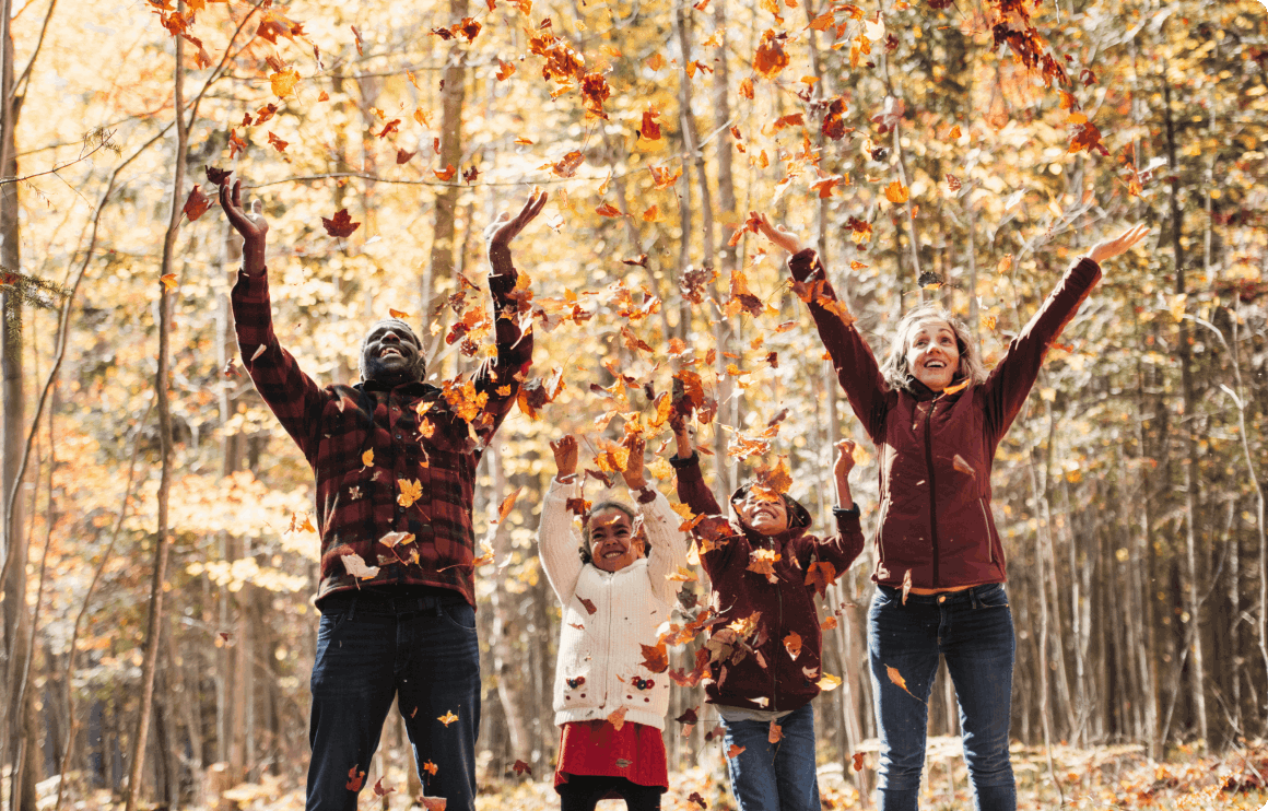 Photo of a family playing with leaves in a forest