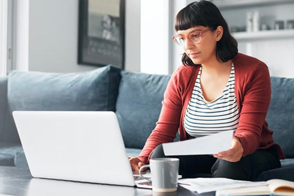 Young woman sitting on a sofa, working on her computer