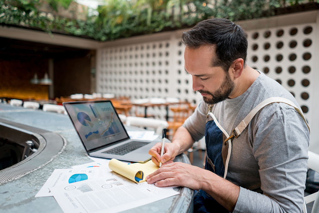 Photo of a man writing in a notebook on a terrace