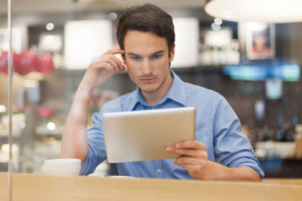 Young man concentrating, sitting in front of a tablet