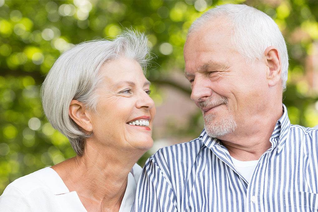 Photo of a retired couple looking and smiling at each other 