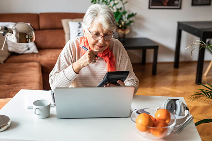 Lady holding a calculator and looking at her laptop computer