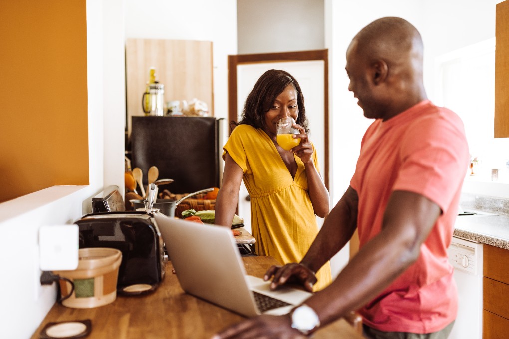 Image of a couple chats in the kitchen while surfing the web.