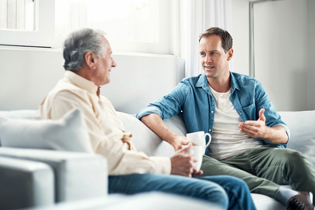 Photo of two men sitting and chatting on a sofa