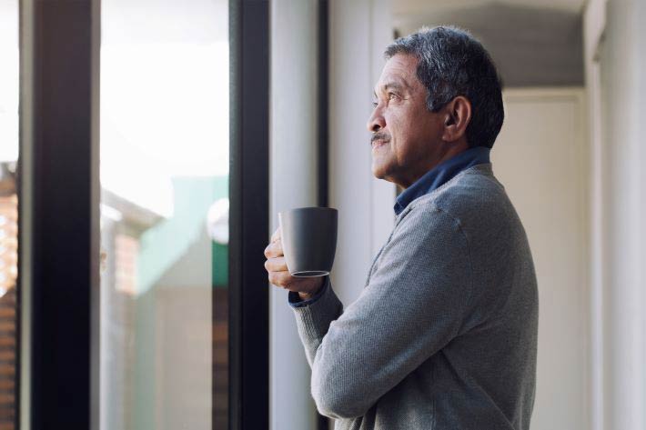 Man drinking coffee in front of window