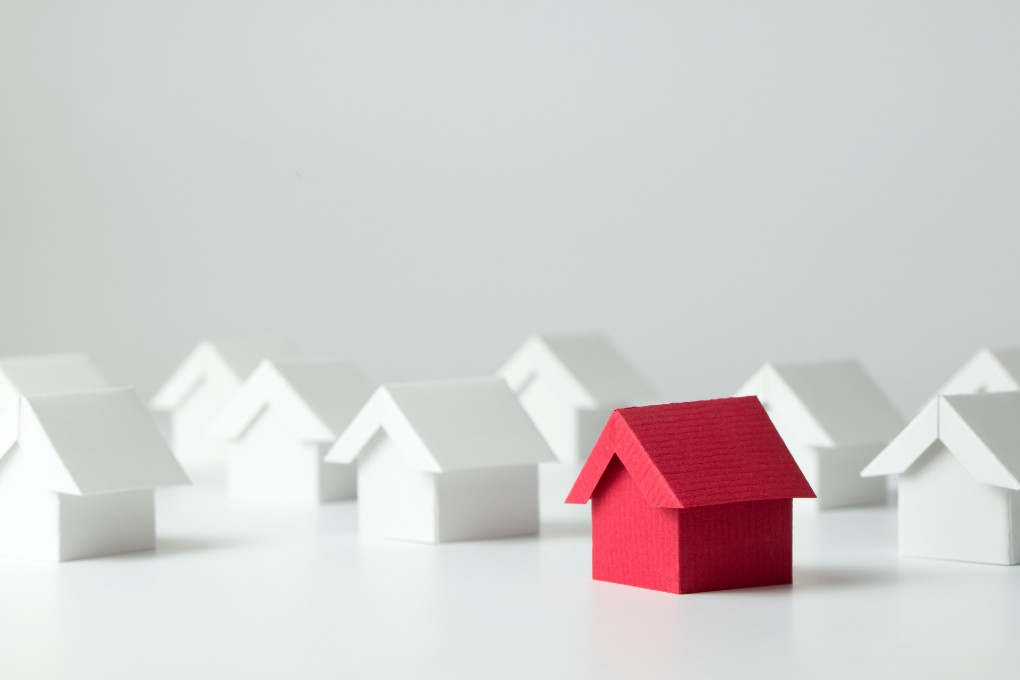 Image of several white cardboard houses and a red one