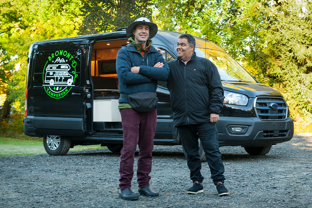 Photo of a National Bank advisor and their client smiling next to a minivan equipped for camping